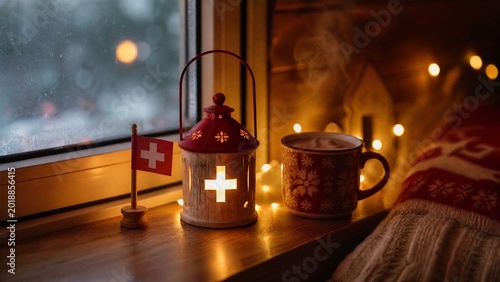 sill. Swiss lantern and flag on window sill with fairy lights and hot chocolate. representing cultural heritage and milestone achievements.
