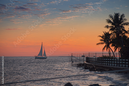 Foto Boats and people walk along the seashore enjoying the natural sunset among palm
