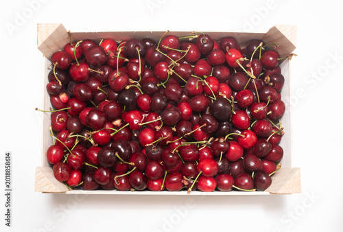 Konstfotografi Top view of a wooden crate full of fresh, ripe, sweet summer cherries on white