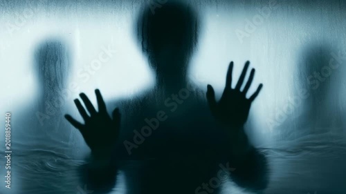 Man moving hands across wet fogged glass in cinematic dark atmosphere
