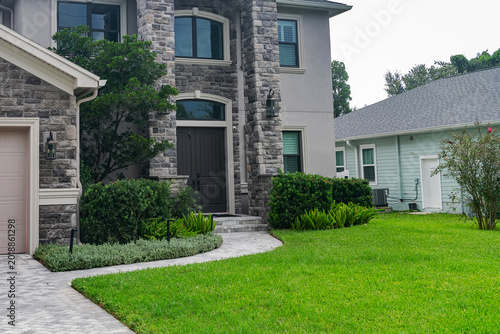 Tidy tropical lawn with sculpted greenery. Elegant curb appeal.