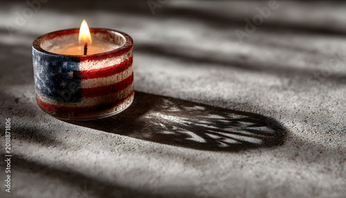 The light of an American flag holder creates a shadow on a gray surface, representing remembrance or patriotism.