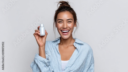 Happy Wellbeing : A joyful young woman radiates health and vitality as she holds a bottle of medicine or supplements, smiling broadly.