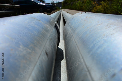 Slika na platnu Long steel pipes of large diameter from a low angle in perspective along the roa