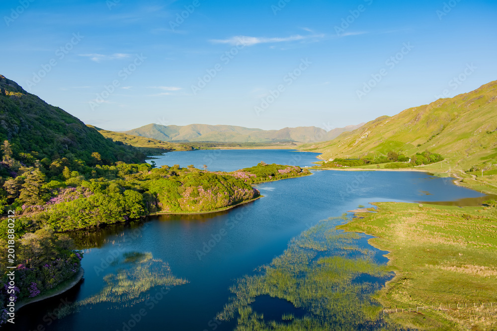 Naklejka premium Pollacappul Lough near Kylemore Abbey glows in evening light beneath the mountains of Connemara, County Galway. A scenic travel landscape about lakes, valleys, and the Wild Atlantic Way.