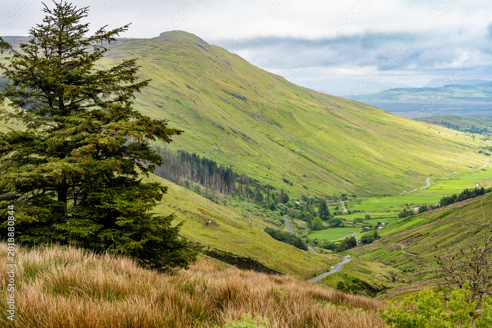 Obraz premium Glengesh Pass winding through a green mountain valley in County Donegal, Ireland. A scenic road landscape of the Wild Atlantic Way and remote Irish highlands.