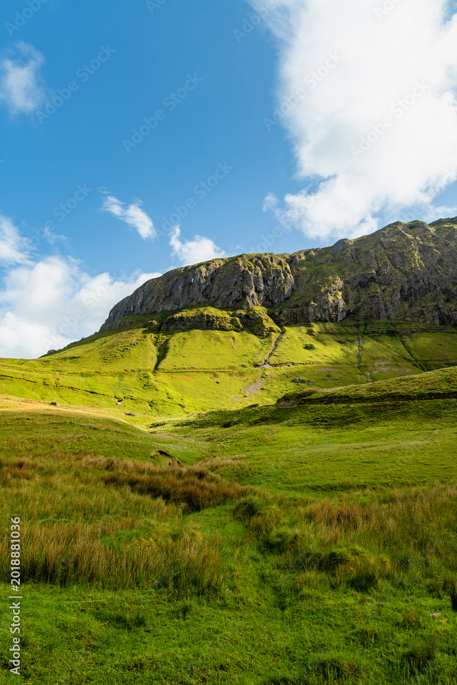 Naklejka premium Gleniff Horseshoe in County Sligo, Ireland, with rolling grassland beneath steep limestone mountains and bright clouds. A scenic drive through one of Irelands classic valleys.