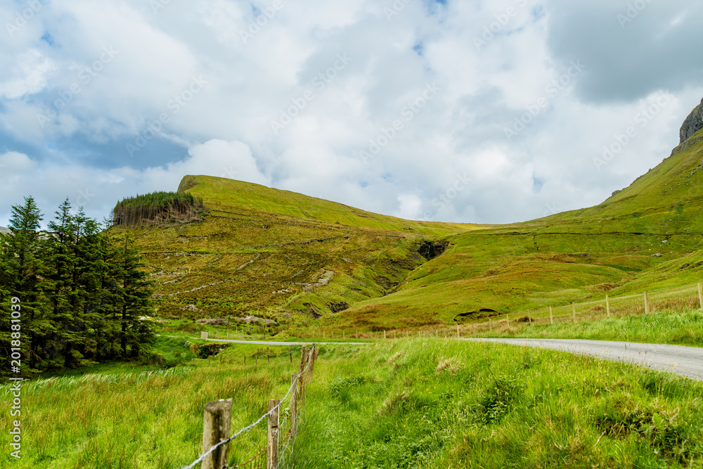 Naklejka premium Gleniff Horseshoe in County Sligo, Ireland, with rolling grassland beneath steep limestone mountains and bright clouds. A scenic drive through one of Irelands classic valleys.