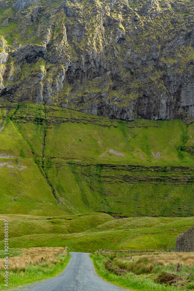 Naklejka premium Gleniff Horseshoe in County Sligo, Ireland, with rolling grassland beneath steep limestone mountains and bright clouds. A scenic drive through one of Irelands classic valleys.