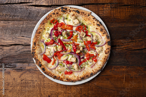 Foto Vegetarian pizza with red peppers and red onion on rustic wooden table, overhead