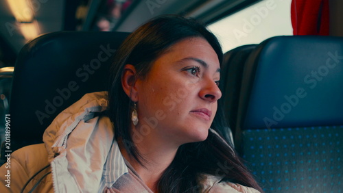 Schilderij op canvas Woman sitting on train looking out window with pensive thoughtful expression as