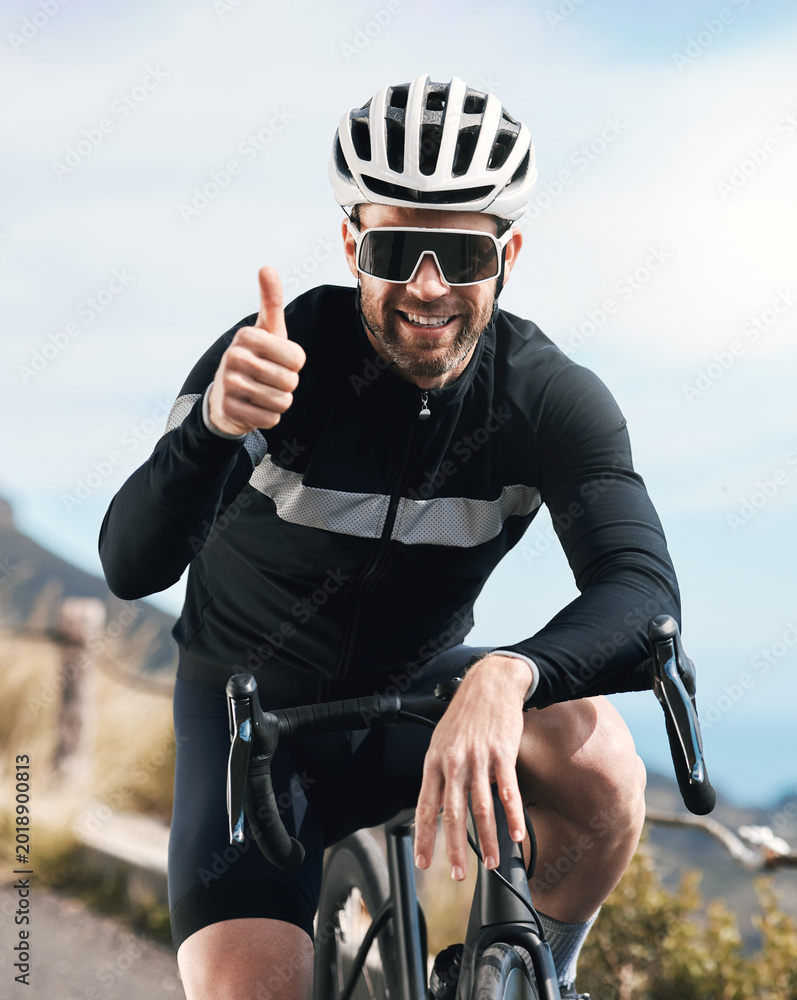 Naklejka premium Man, bike and thumbs up outdoor for training, fitness or achievement on mountain road. Athlete person, smile and sunglasses for workout, exercise and cyclist with hand gesture for win in nature