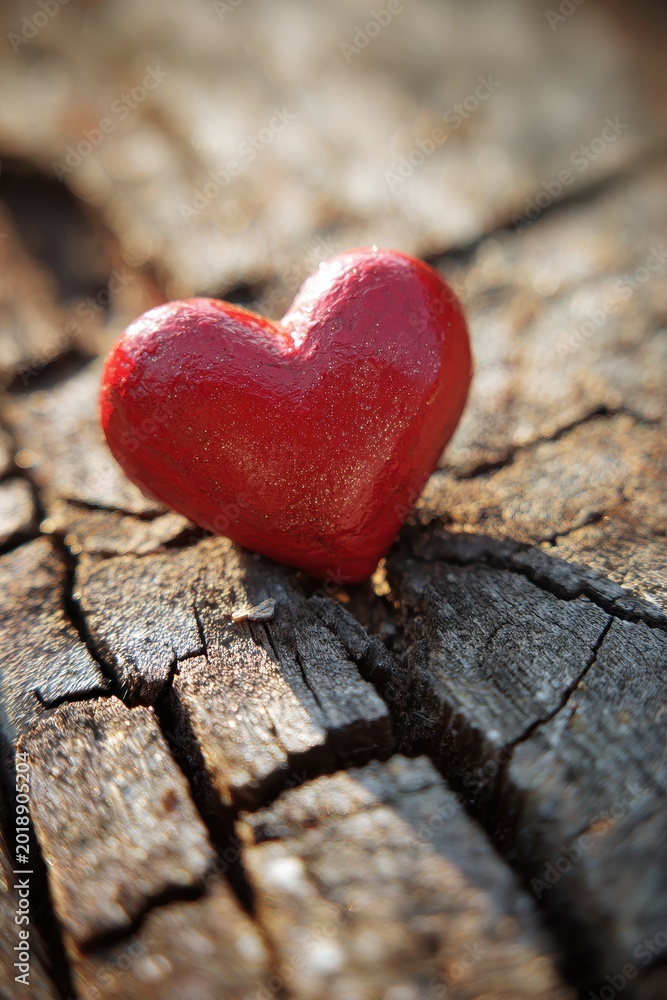 Fototapeta premium Red heart-shaped coupon on a weathered cracked wooden surface