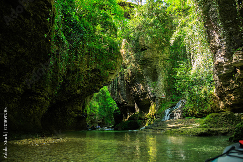 Slika na platnu Scenic view of a lush green canyon with clear river water and rocky cliffs covered in vegetation