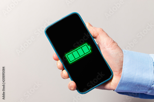 Hand holding smartphone showing full battery