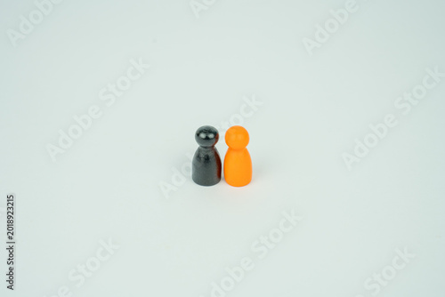 Photos Two simple game pieces one black one orange stand close together on a plain whit