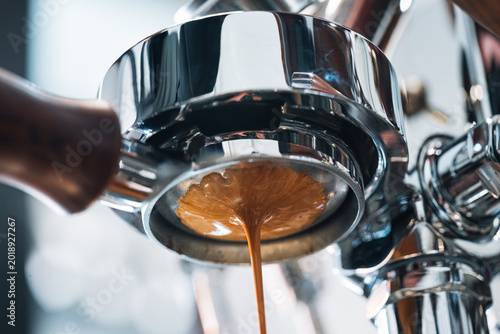 Espresso coffee pouring from bottomless portafilter at coffee maker