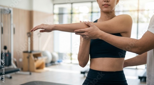 Physical therapist stretching arm of female athlete in modern clinic