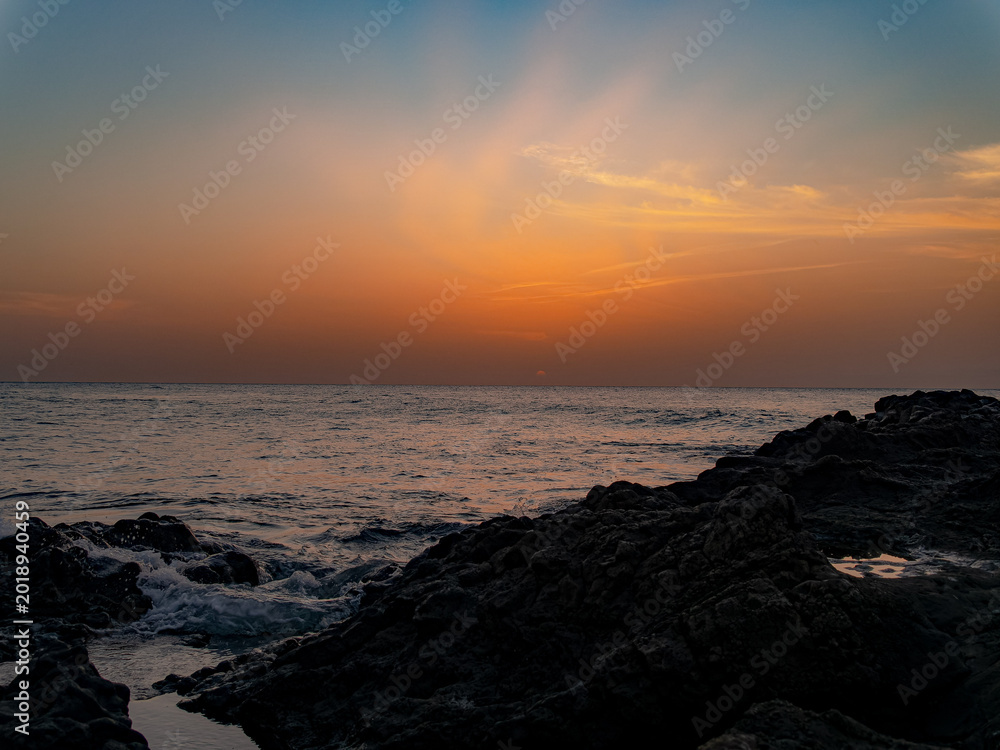 Fototapeta premium Ocean waves crashing on rocks during sunset