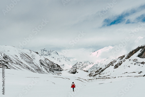 Bild auf Leinwand Mujer en la nieve rodeada de montañas durante una aventura invernal al aire libre