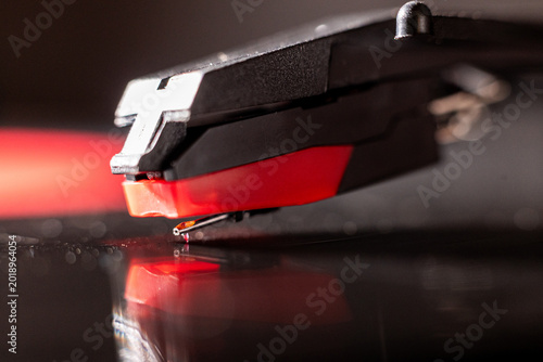 Fotografija Close-up of a turntable stylus playing a vinyl record with red illumination