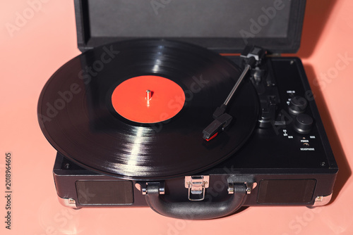Fényképezés Vinyl record playing on portable turntable with black and red design