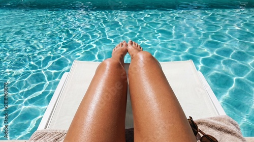 Obraz na plátně First-person point of view of bare feet resting by the clear blue water of a swimming pool or beach