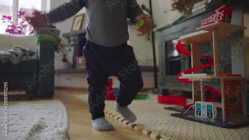 Fotografi Toddler pushing up from floor while holding toy showing effort balance and early