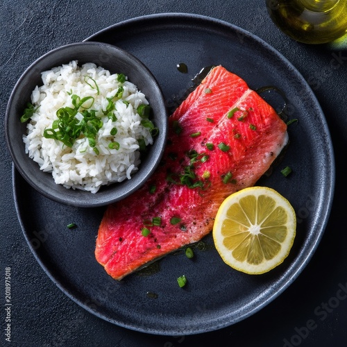 Salmon Fillet Served With Rice and Lemon on a Black Plate in a Kitchen Setting