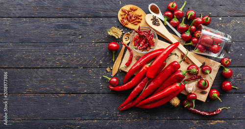 Quadro em tela Vibrant red chili peppers on rustic wooden board with spices and garlic