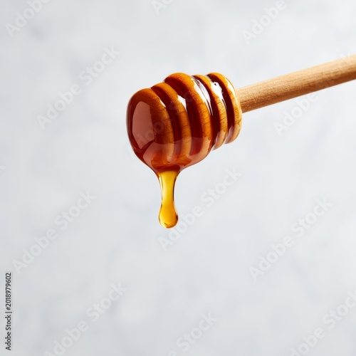 Dripping Honey From a Wooden Dipper Above a Light Background
