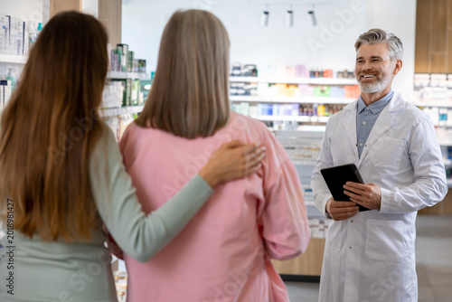 Bild auf Leinwand Senior Caucasian male pharmacist with gray hair holding digital tablet and consu
