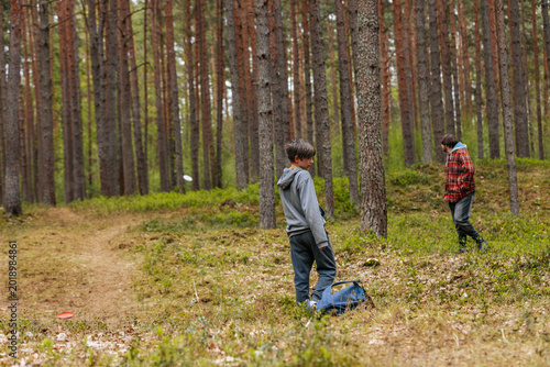 Canvas Print Two boys playing disc golf in a forested area, one boy wearing a gray hoodie and