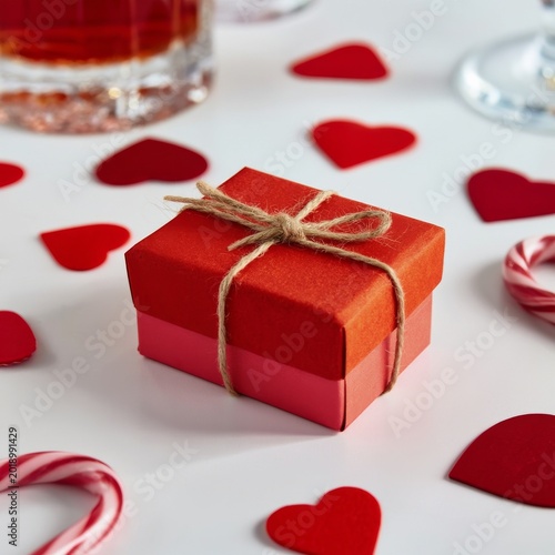 Gift Box Sits on Table Surrounded by Heart Shapes and Candy Canes During a Ce...