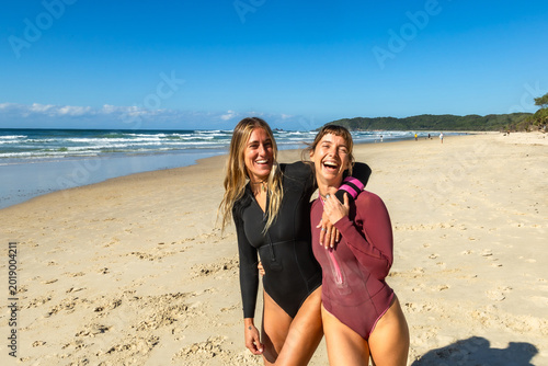 Konstfotografi Surfing friends laughing embracing on byron bay beach