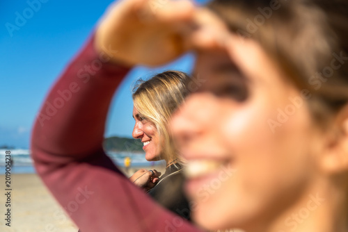 Fotografija Young woman smiling while shielding eyes on beach
