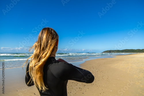 Foto Woman surfer in wetsuit looking at ocean waves