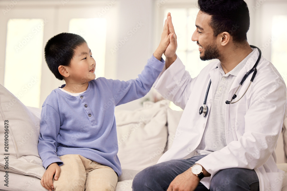 Obraz premium Doctor, boy and high five in home with support for checkup, healthcare and smile for wellness in lounge. Pediatrician, Asian man and child with celebration, happy or motivation for services at house