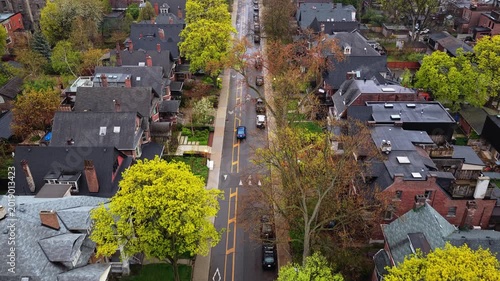 Urban landscape showcasing residential district with street traffic and vibrant spring foliage, classic Victorian architecture and neighborhood life in North America