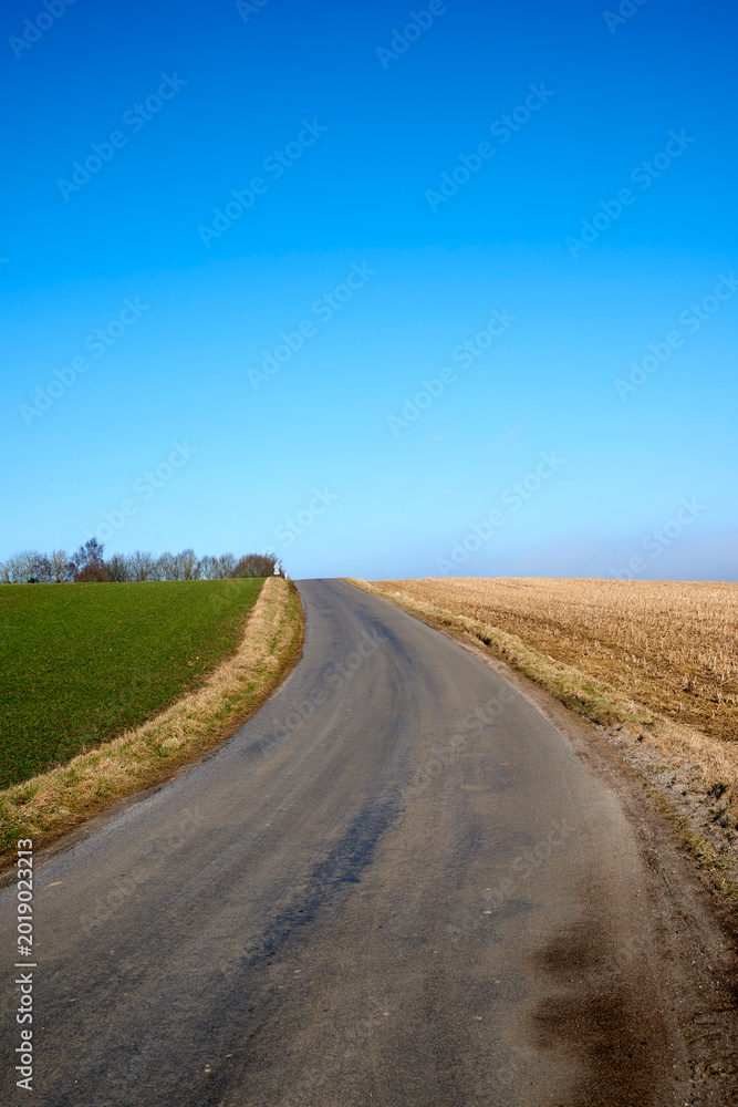 Naklejka premium Landscape, blue sky and road in countryside for travel, tourist destination and journey outdoor. Empty, background and street with scenic route, highway and space for vacation, trip and holiday