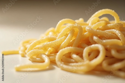 Flour long pasta close-up on beige surface