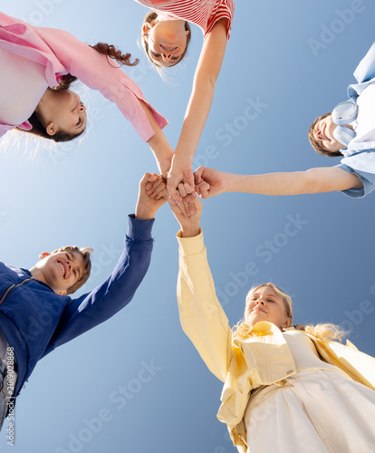 Teenagers joining fists in unity under sky