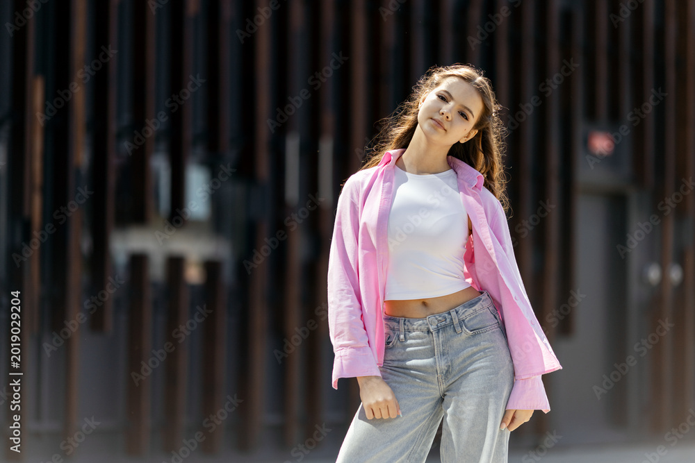 Fototapeta premium Young woman posing in casual street fashion style