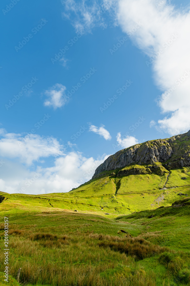 Obraz premium Gleniff Horseshoe in County Sligo, Ireland, with rolling grassland beneath steep limestone mountains and bright clouds. A scenic drive through one of Irelands classic valleys.