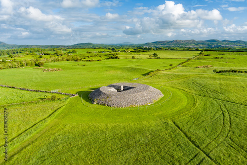 Aerial view of Carrowmore Passage Tomb surrounded by bright green fields in County Sligo, Ireland. An ancient megalithic monument in the Irish countryside.