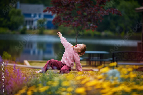 Expressive Little Girl Playing Outdoors by the Lake - Joyful Childhood Energy in Blooming Summer Park
