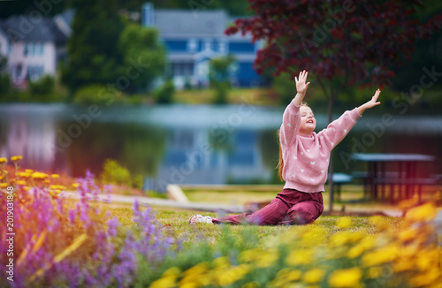 Expressive Little Girl Playing Outdoors by the Lake – Joyful Childhood Energy in Blooming Summer Park