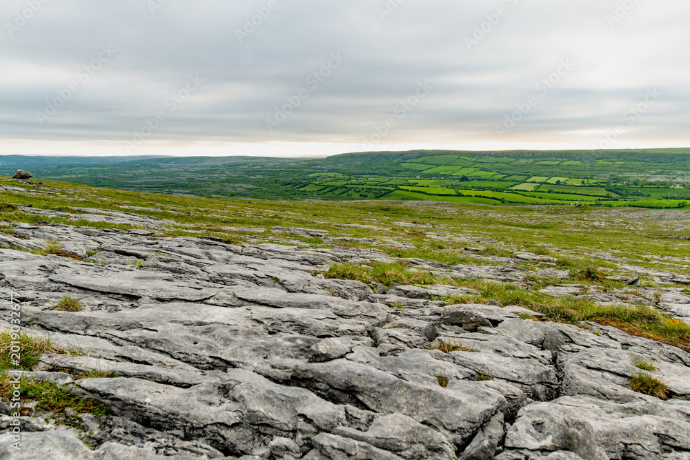 Naklejka premium Limestone pavement landscape in Burren National Park, County Clare, Ireland. Wild karst scenery on the Wild Atlantic Way with views across the Irish countryside.