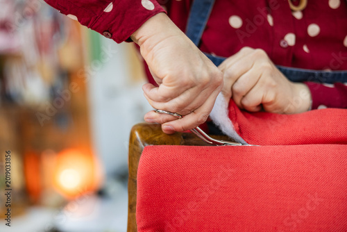 Upholsterer hand cutting red fabric during furniture renovation