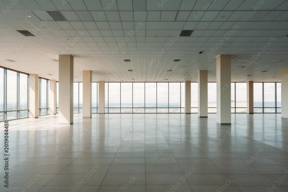Fototapeta premium Large empty office interior featuring tall glass windows overlooking a city skyline